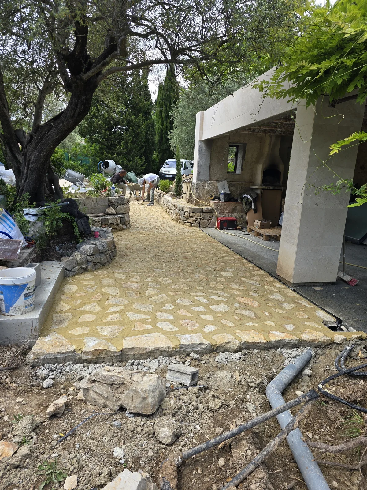 Allée en pierre naturelle (calade) et cuisine d'été réalisées par Atlas Construction dans un jardin méditerranéen
