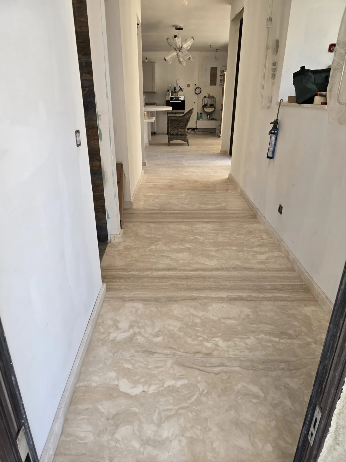 Couloir au sol en travertin poli ouvrant sur une cuisine, rénovation intérieure par Atlas Construction